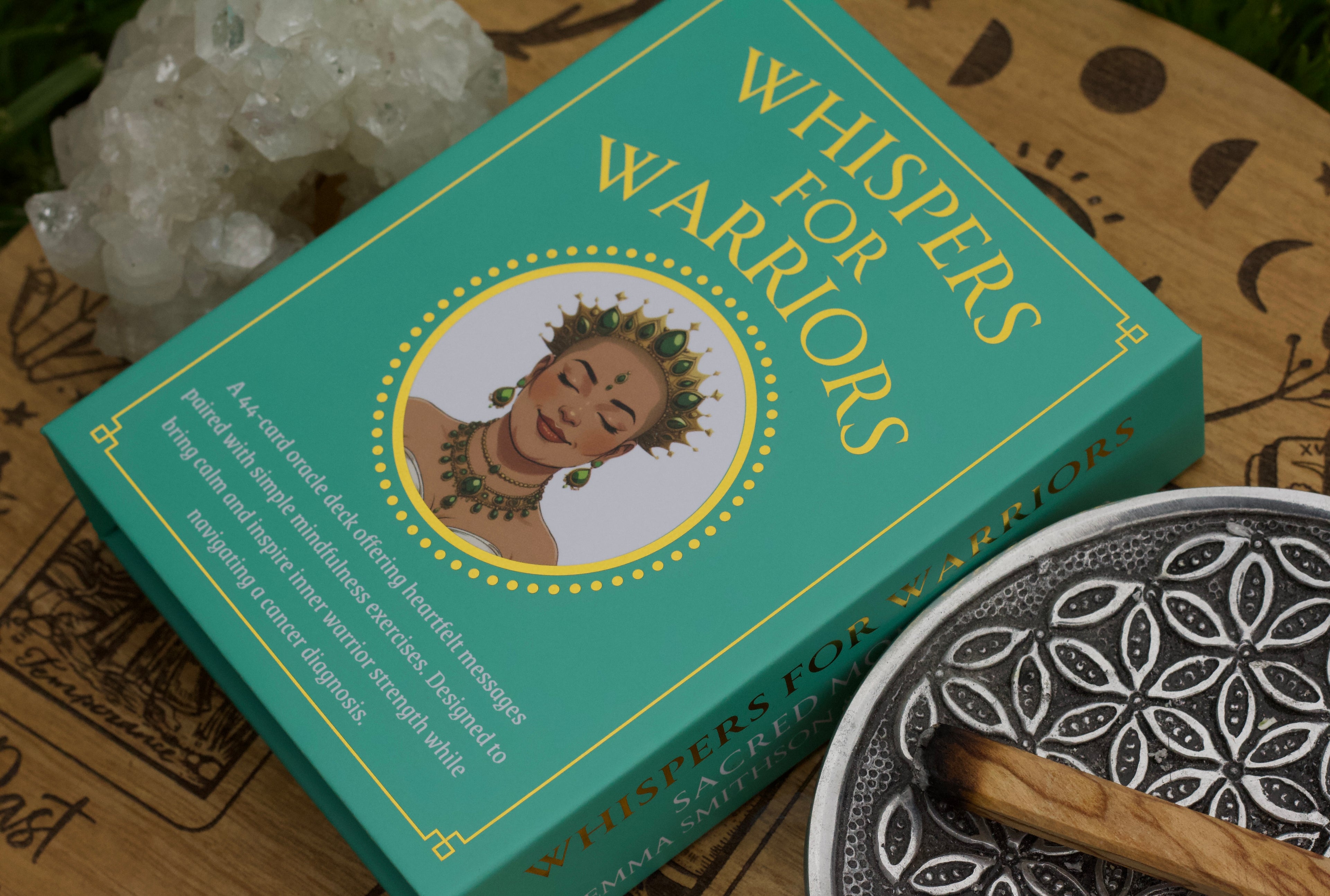 Oracle deck, 'Whispers for Warriors' with a decorative cover on a wooden surface.